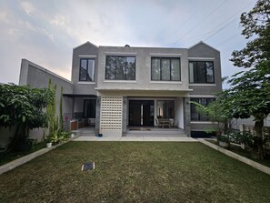 A modern two-story house with a flat roof, large windows, and a well-maintained lawn. - Wonderful 5-bedroom house with AC in charming Bandung and Mountain Views. (Bandung)
