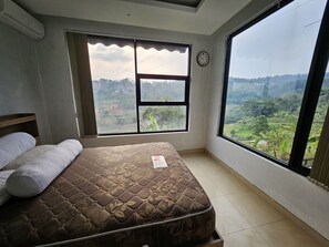 Een slaapkamer met een bed, een raam en een klok aan de muur.
