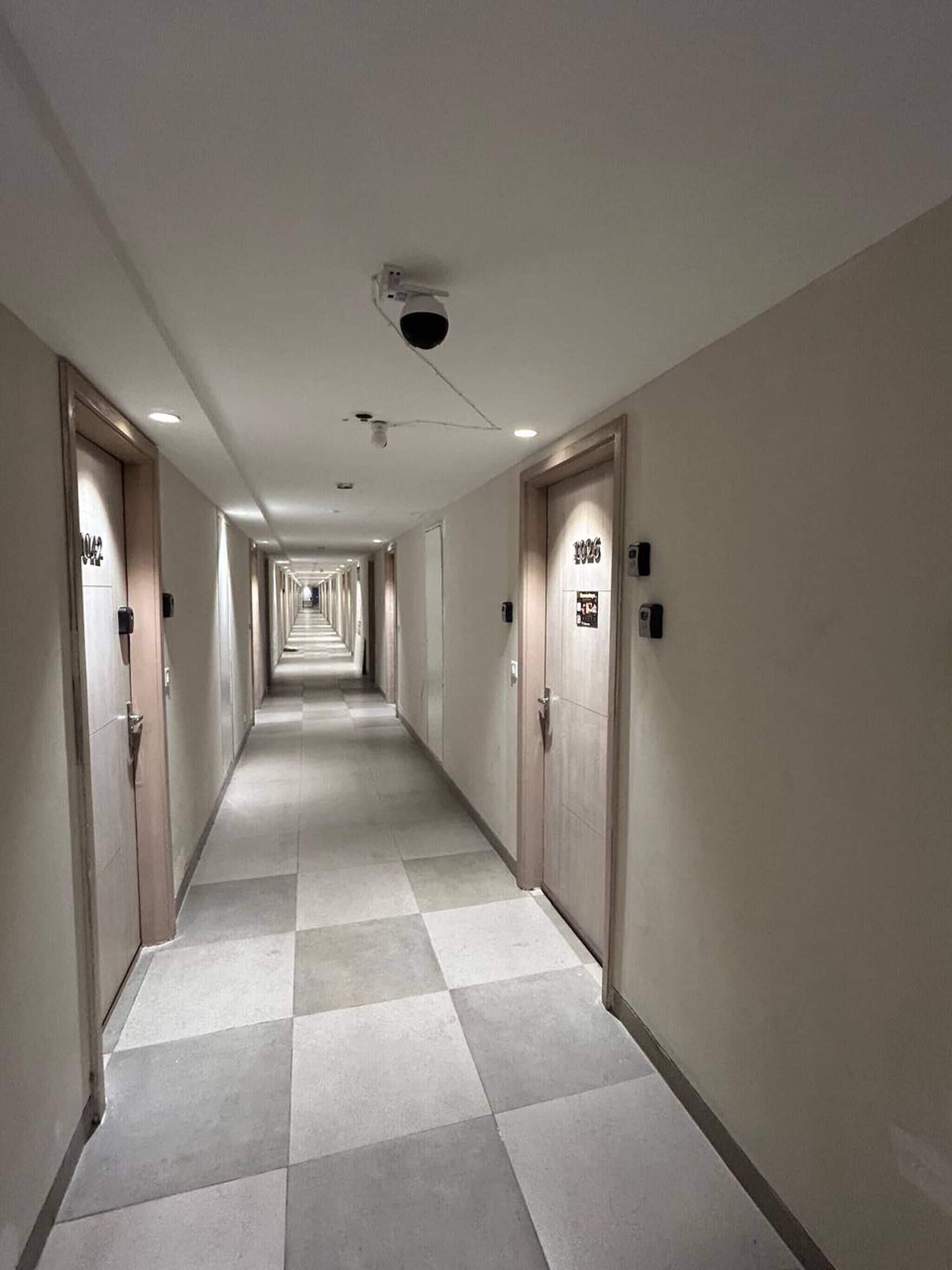 A hotel corridor with doors on both sides, each marked with room numbers.