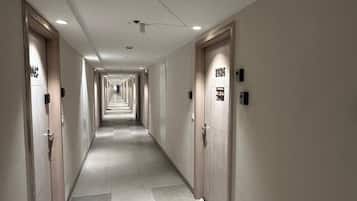 A hotel corridor with doors on both sides, each marked with room numbers.