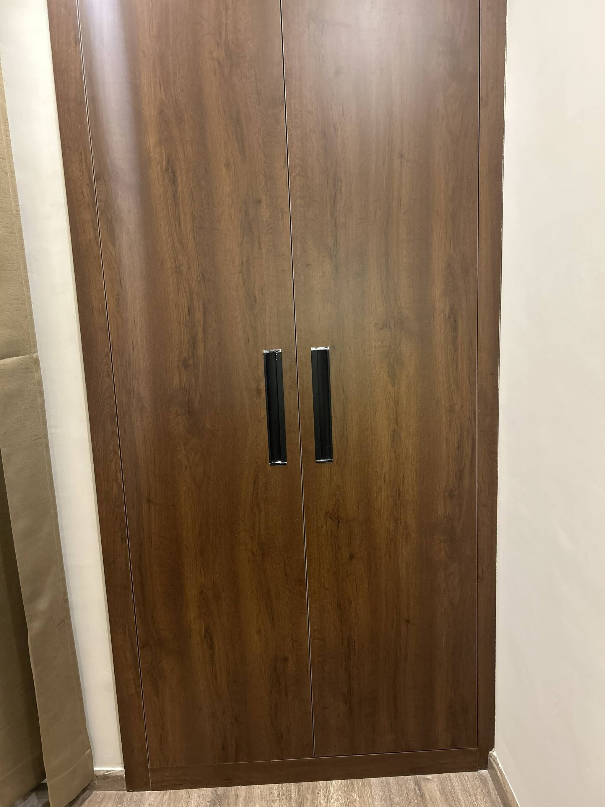 Un amplio armario de madera con dos puertas y un tirador central.
