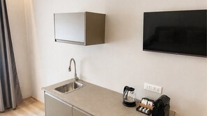 A compact kitchenette with a sink, a coffee maker, and a flat-screen TV mounted on the wall. - Room 3 (Torino)