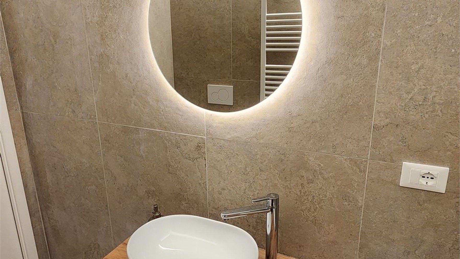 Ein Badezimmer mit rundem Spiegel, Waschbecken und Handtuchhalter.
