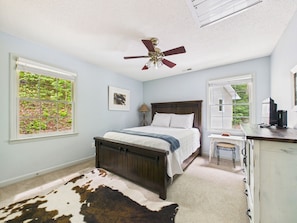 A bedroom with a bed, a desk, a ceiling fan, and large windows. - NEW LISTING! Koi Pond Lodge by Chatuge Home Concierge | Near Lake Chatuge & Mountain Views (HIAWASSEE)