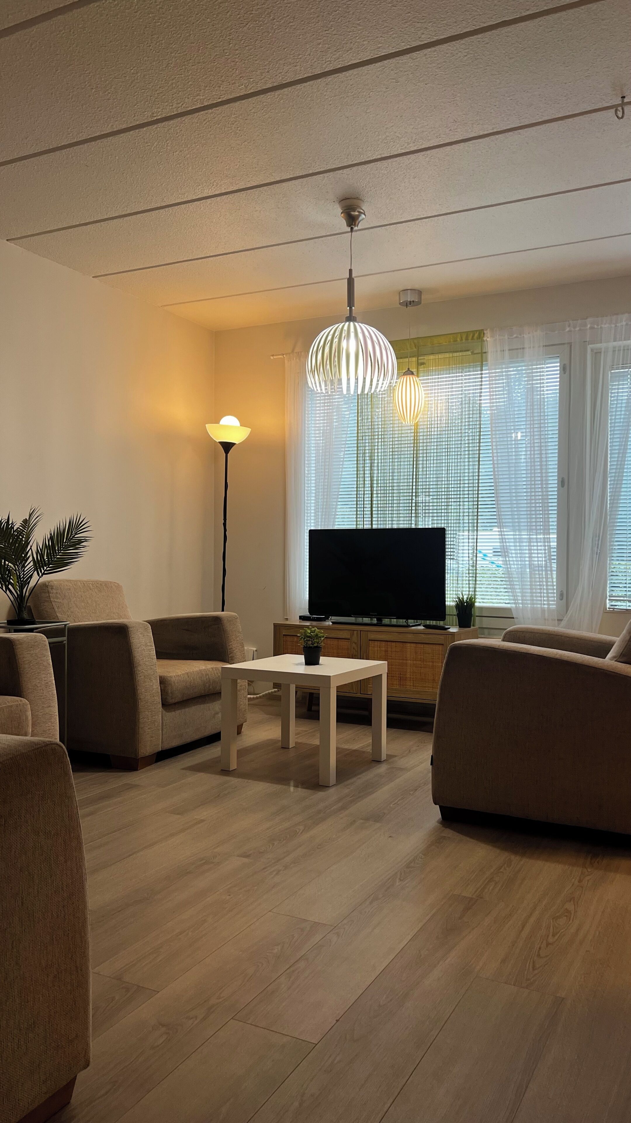 A modern living room with a flat-screen TV, two sofas, a coffee table, and a pendant light.