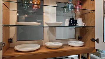 Et køkken med træbordplade, glas hylder og en hængende lampeskærm.