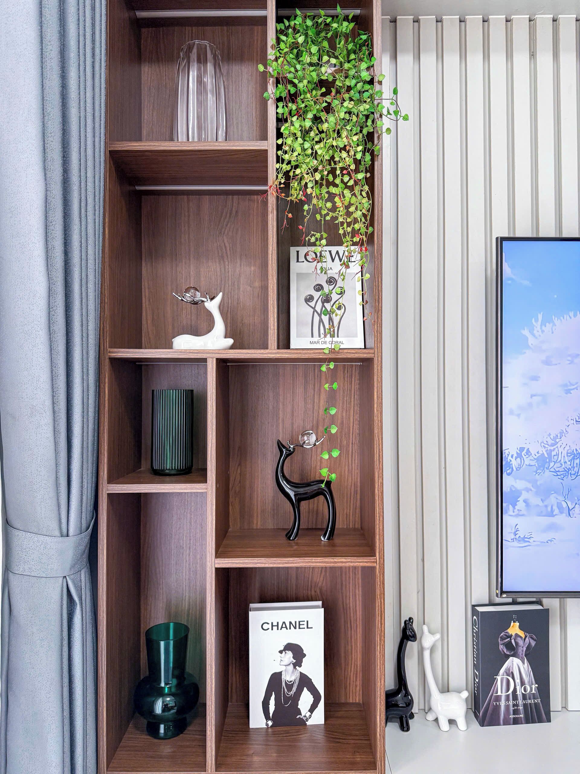 Ein Holzregal mit Dekoration, einer Topfpflanze und einem gerahmten Bild.