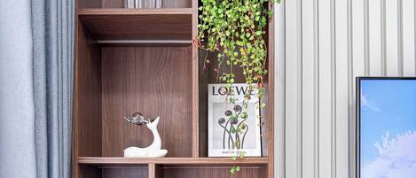 Une étagère en bois ornée d’objets décoratifs, d’une plante en pot et d’un tableau encadré.