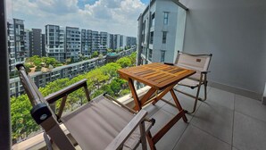 En balkong med ett träbord och två stolar, med utsikt över ett bostadsområde med moderna byggnader och grönområden.