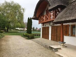 A traditional building with a thatched roof, wooden shutters, and a stone pathway leading to the entrance. - Spacious 3-bedroom apartment in tranquil Cserszegtomaj, Balaton view, pool, AC (Cserszegtomaj)