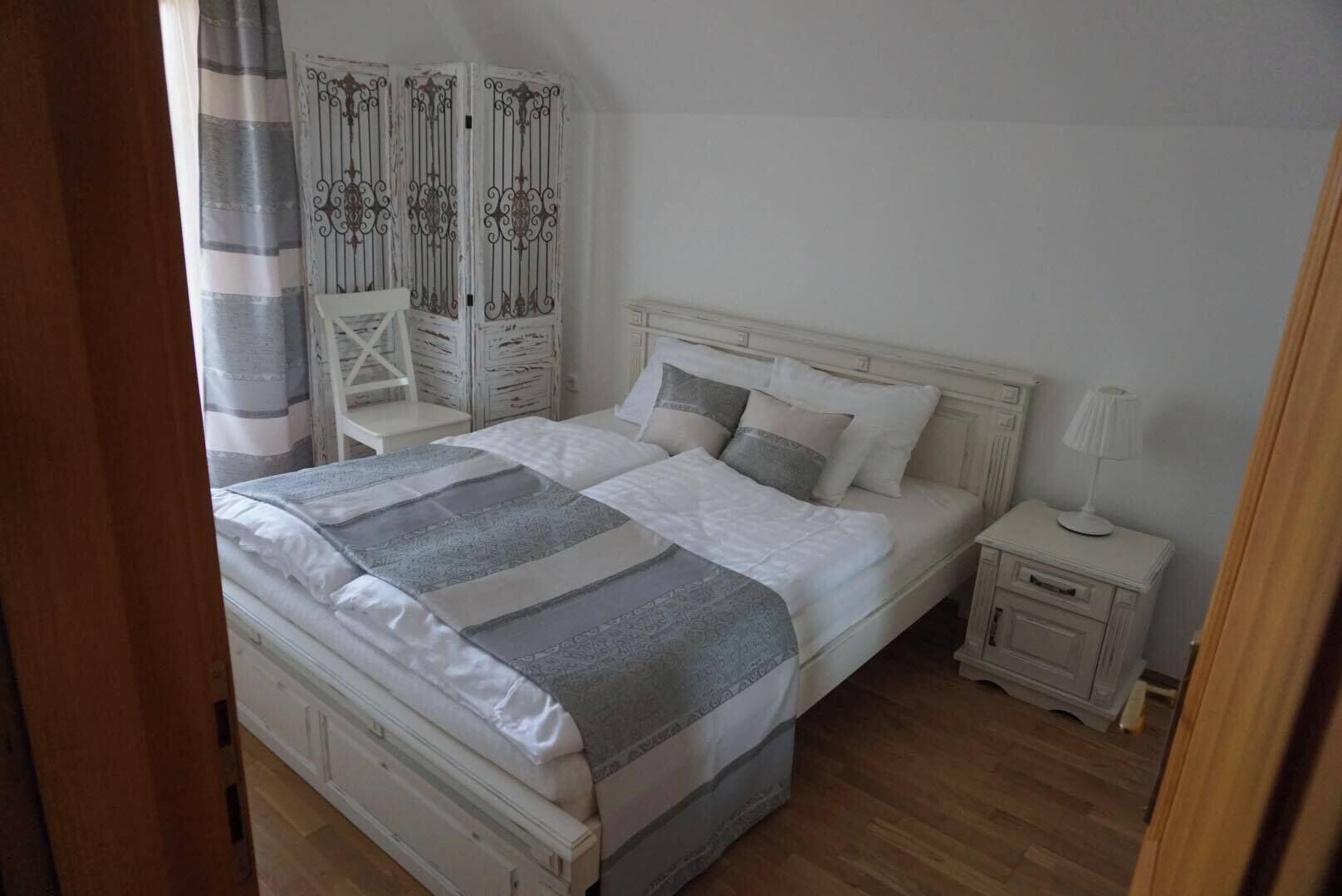 Une chambre à coucher comprenant un lit, des tables de chevet, une chaise et une armoire.