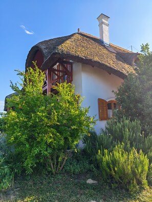 A house with a thatched roof, wooden shutters, and a chimney. - Spacious 3-bedroom apartment in tranquil Cserszegtomaj, Balaton view, pool, AC (Cserszegtomaj)