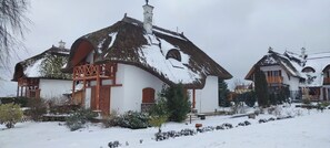 Una casa tradicional con techo de paja, un porche de madera y un paisaje nevado.