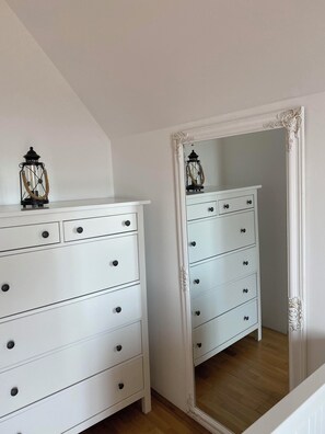 Une pièce avec une commode blanche, un miroir doté d’un cadre orné et une lanterne suspendue.