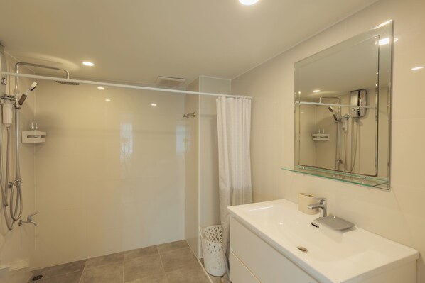 A modern bathroom with a glass shower enclosure, a white sink, and a large mirror. - Terrific 1-bedroom condo with AC in charming Chiang Mai (Chiang Mai)