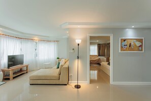 A modern living room with a sofa, a TV, a floor lamp, and a painting on the wall. - Terrific 1-bedroom condo with AC in charming Chiang Mai (Chiang Mai)