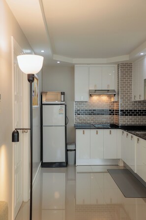 A modern kitchen with white cabinets, a black countertop, and a built-in microwave. - Terrific 1-bedroom condo with AC in charming Chiang Mai (Chiang Mai)
