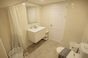 A bathroom with a white sink, mirror, and toilet. There is a shower curtain, a white basket, and a welcome mat. - Terrific 1-bedroom condo with AC in charming Chiang Mai (Chiang Mai)