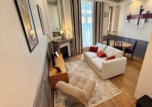 A modern living room with a sofa, armchair, and a dining table with chairs. - Le Sarciron 299, Le Mont Dore, 2–4 people (Mont-Dore)