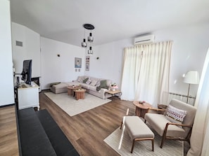 Ein modernes Wohnzimmer mit einer Couch, einem Couchtisch und einem Fernseher.