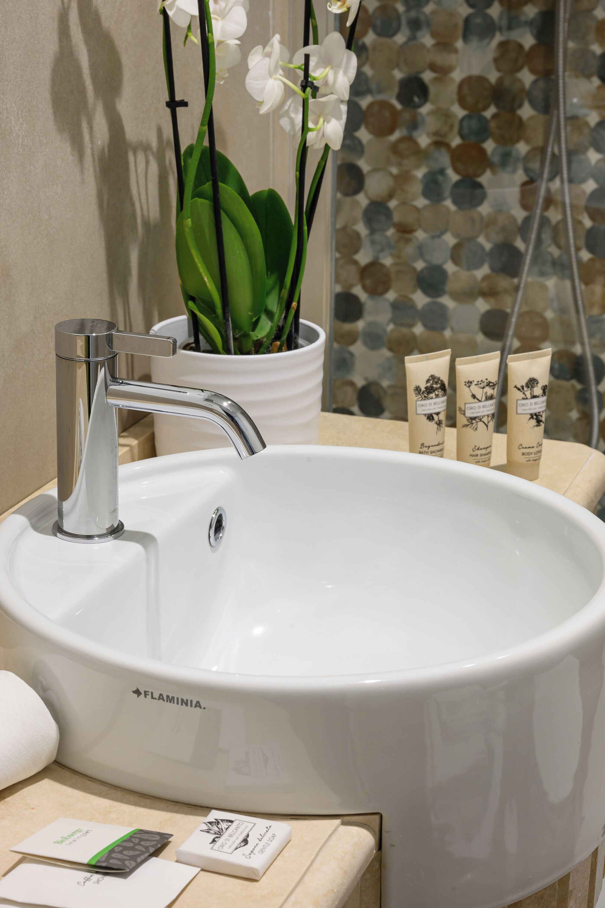 A bathroom with a white sink, a potted plant, and toiletries.