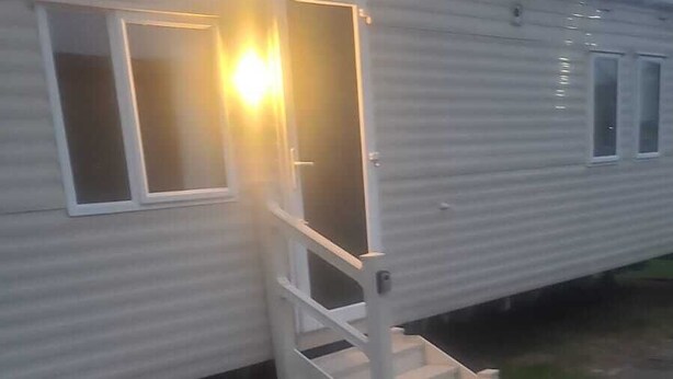 Ein Wohnmobil mit einer Veranda und einer Treppe zum Eingang.