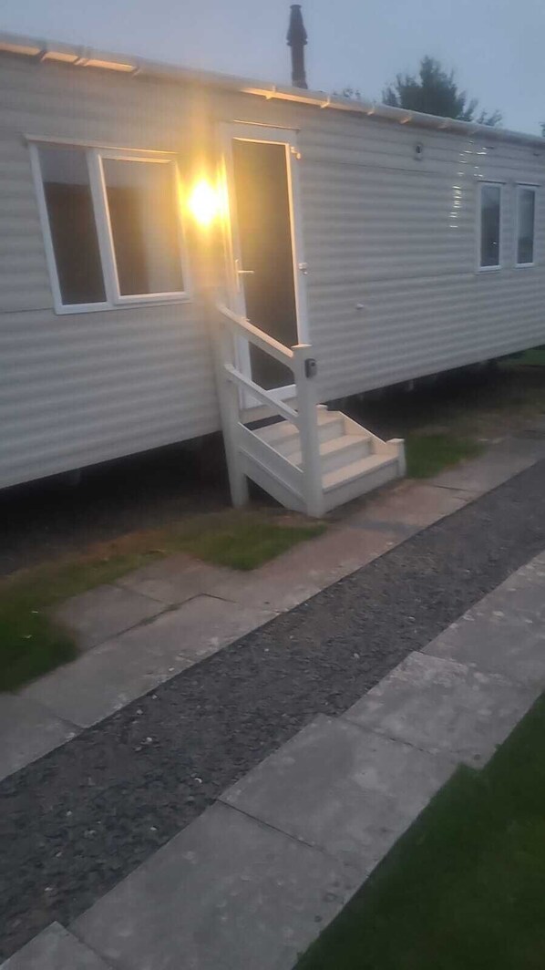 Ein Wohnmobil mit einer Veranda und einer Treppe zum Eingang.