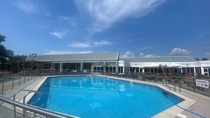 A swimming pool with a clear blue water surface, surrounded by a metal fence and a covered area with umbrellas. - Beautiful Caravan minutes from Cartmel & Grange-over-Sands, Lakes are nearby. (Flookburgh)