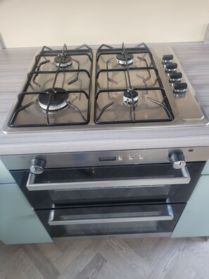 Een keuken met een vierpits fornuis en een ingebouwde oven.