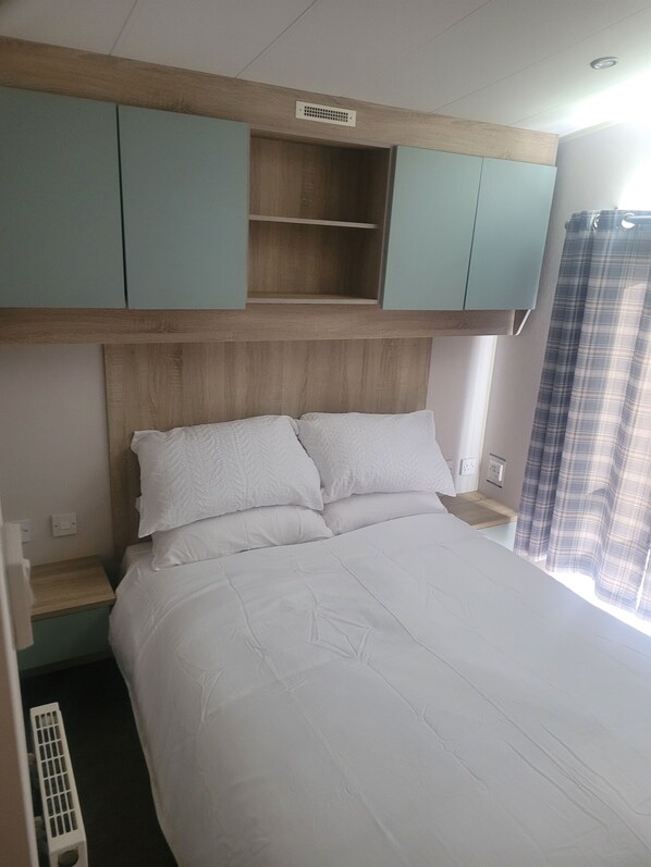 A bed with white bedding, a wooden headboard, and a light blue cabinet above it.