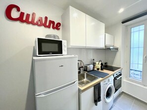 A compact kitchenette with a microwave, toaster, sink, and a washing machine. - Comfortable and quiet studio in the heart of the 15th, easy access to all of Paris (paris)