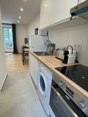 A compact kitchen with a washing machine, a built-in oven, and a countertop with a toaster. - Comfortable and quiet studio in the heart of the 15th, easy access to all of Paris (paris)