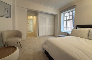 A bedroom with a bed, a chair, a small table, and a closet. - Luxury Pad for couples next to Paddington station (London)