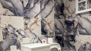 A bathroom with a white sink, toilet, and bidet, marble-patterned walls, and a window. - Guesthouse Sleeps 2 With Parking (Bootle)