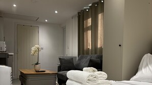 A modern hotel room with a neatly made bed, a bedside table with a vase of flowers, a chair, and a wardrobe. - Guesthouse Sleeps 2 With Parking (Bootle)