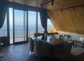 Comedor con vista al océano, amplias ventanas y techo de madera.