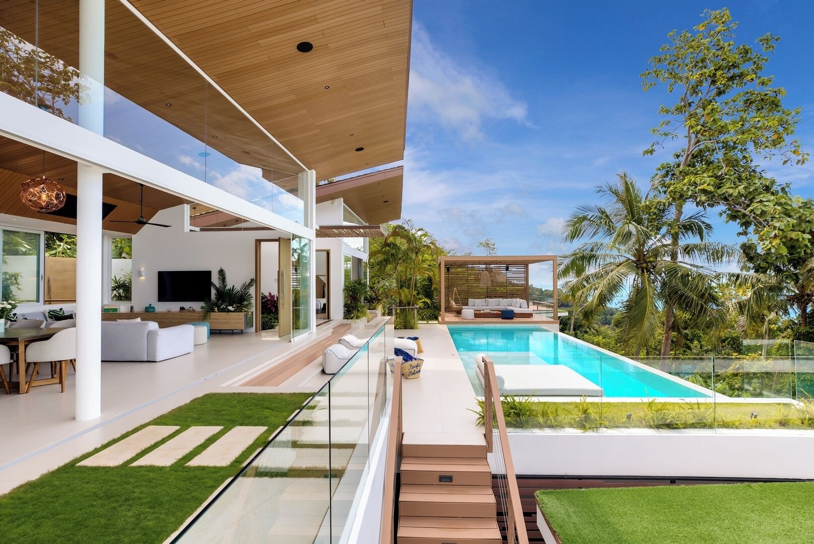 A modern house with a swimming pool, outdoor seating, and a large TV in the living area.