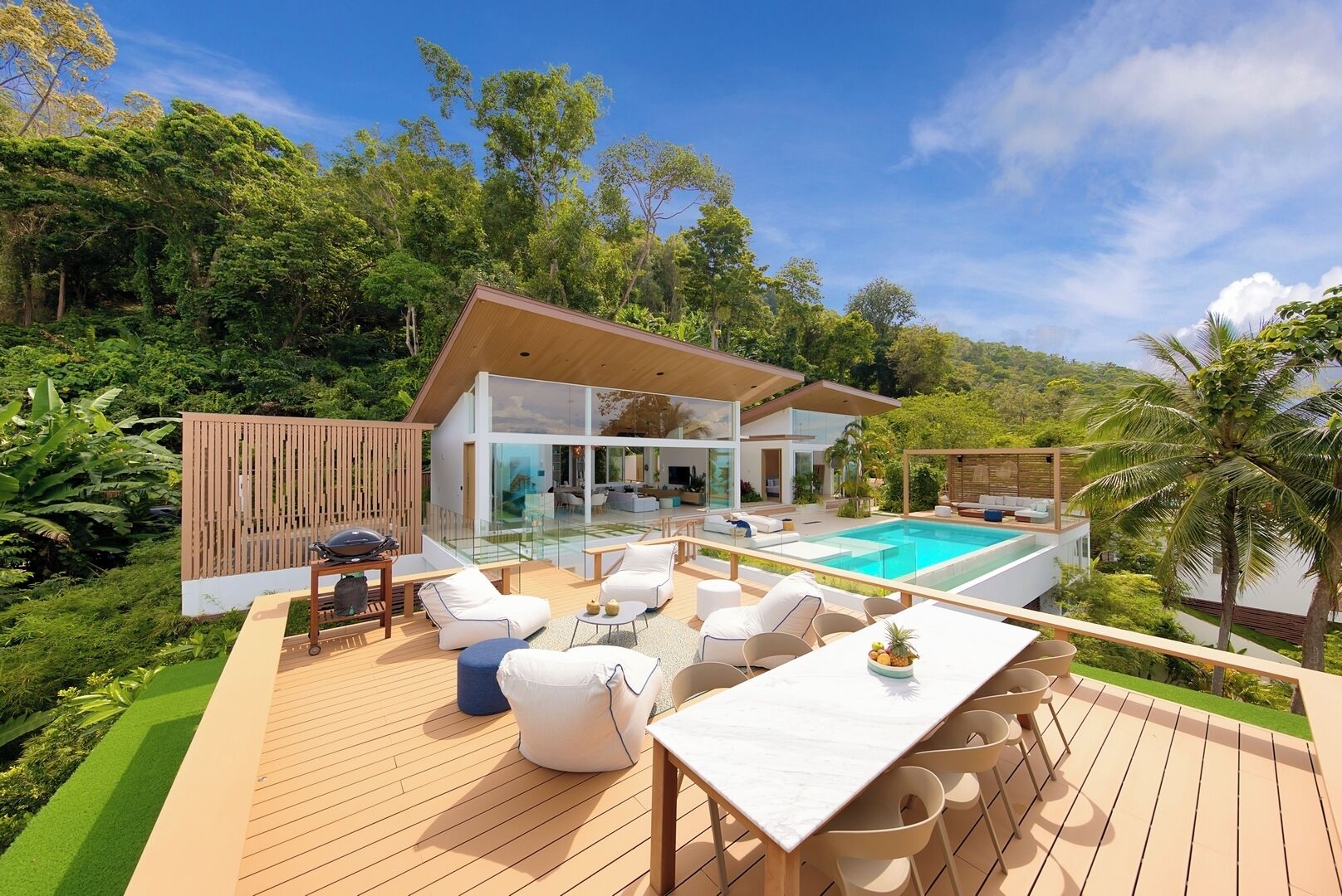 A modern house with a pool, outdoor furniture, and lush greenery.