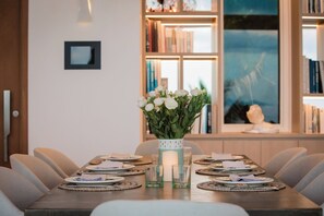 Ein Esstisch, gedeckt mit Tellern, Gläsern und einer Blumenvase.