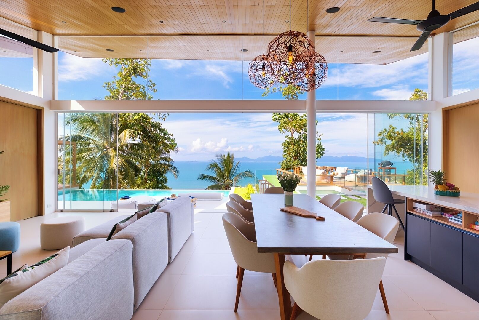 Un interior moderno con comedor, sofás y vistas al océano.