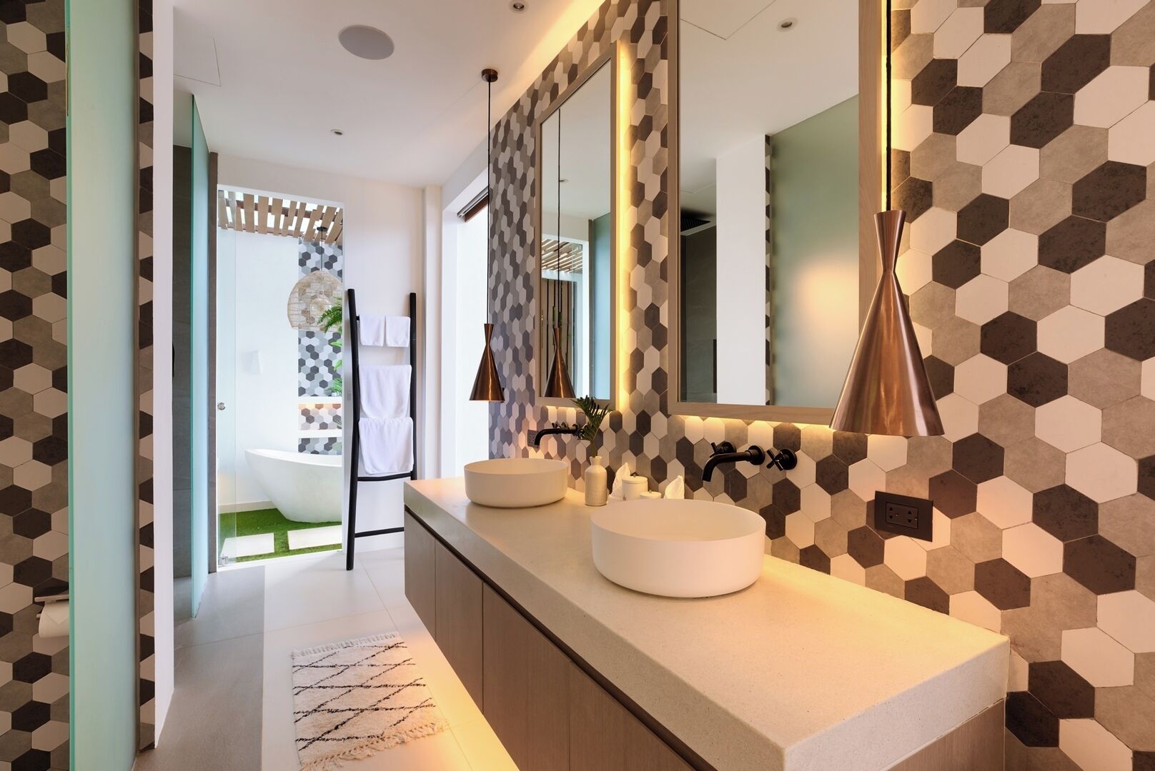 A modern bathroom with a large mirror, two sinks, and a geometric patterned wall.