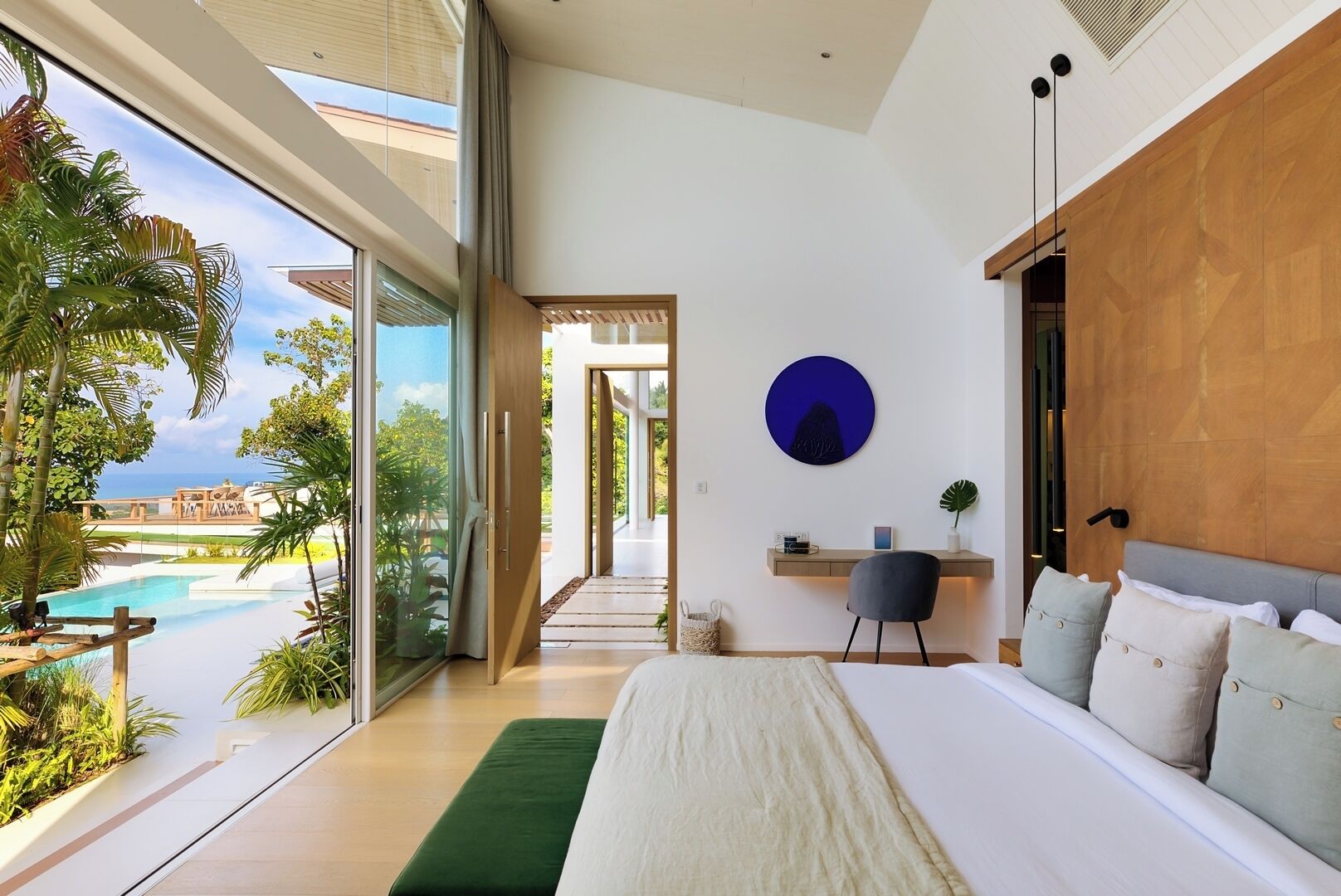 Un dormitorio moderno con una cama grande, un escritorio y vistas a una piscina.