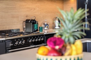 Eine Küche mit Herd, einer Kaffeemaschine und einer Obstschale.