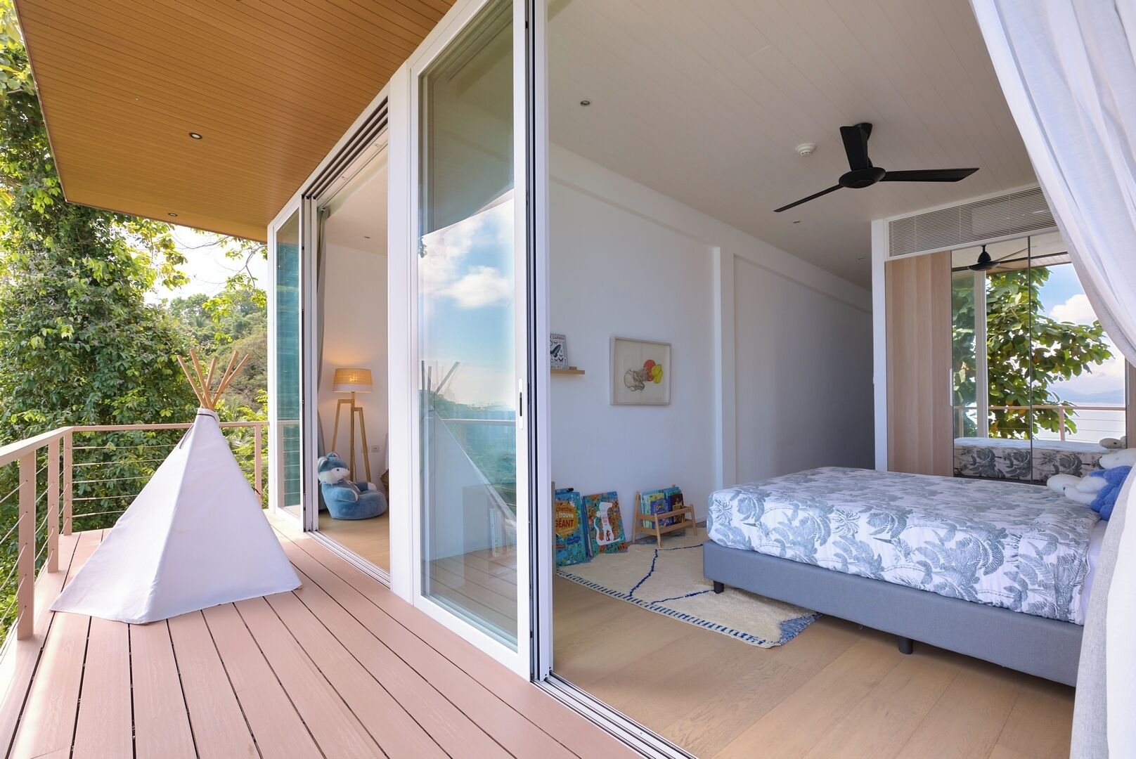 A bedroom with a bed, a ceiling fan, and a view of the outdoors.