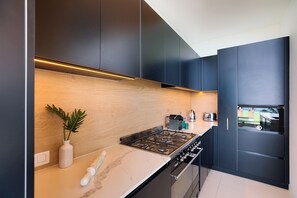 Eine moderne Küche mit dunklen Schränken, einer Holzrückwand und einem Gasherd.
