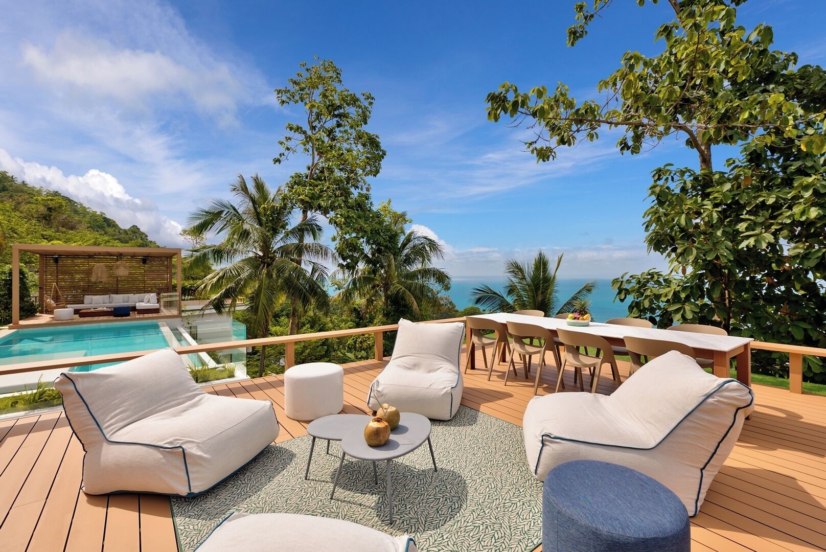 A deck with outdoor furniture, a pool, and a view of the ocean.