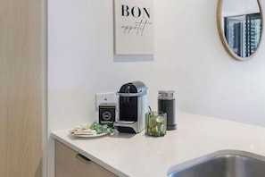 Eine moderne Küche mit Kaffeemaschine, Teezubereiter und einem Glas Wasser auf der Arbeitsfläche.