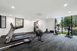 Een sportschool met loopbanden, een hometrainer en krachttoestellen.