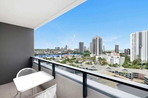 A balcony with a view of a cityscape, including high-rise buildings and a body of water. - Ocean & River Views | Sauna + Steam Rm (Surfers Paradise)