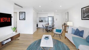 A modern living room with a flat-screen TV, a coffee table, and a sofa. - Ocean & River Views | Sauna + Steam Rm (Surfers Paradise)